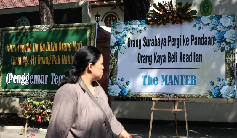 Warga perhtikan karangan bunga yang terpajang di depan Gedung PN Surabaya, Jalan Arjuno, Surabaya, Jawa Timur, Senin (29/7).(Antara/Didik Suhartono)